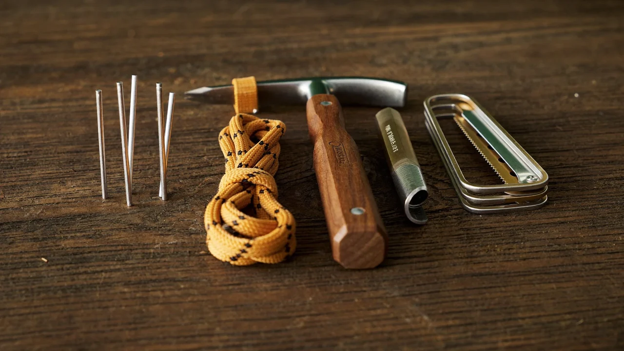 Picchetti, tiranti, mazzuolo e multiutensile disposti su una superficie di legno consumato